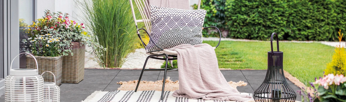 Terrasse mit grauen Terrassenplatten und Sitzmöbeln mit Deko 