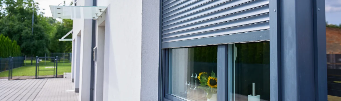 weißes Mehrfamilienhaus mit blau-grauen Fensterrahmen und Außenrollläden