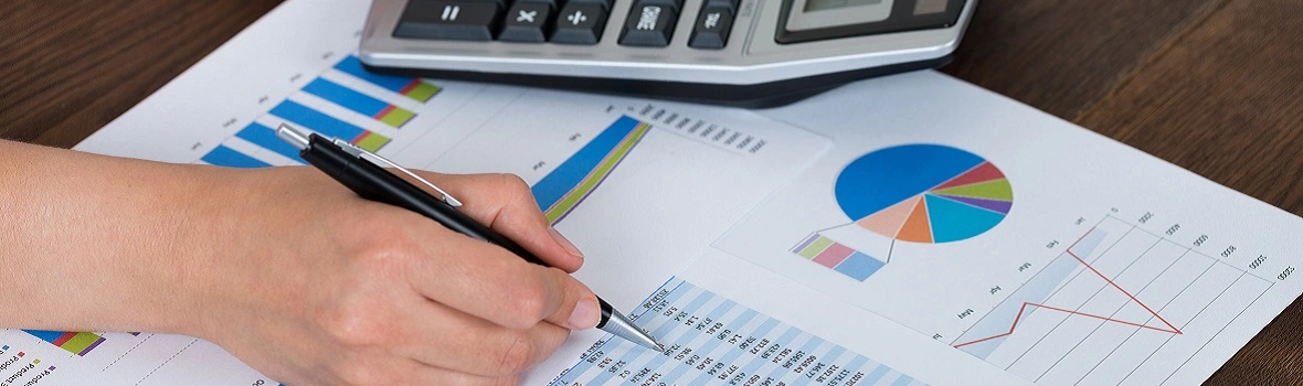 Person arbeitet mit Finanzdiagrammen und Taschenrechner.