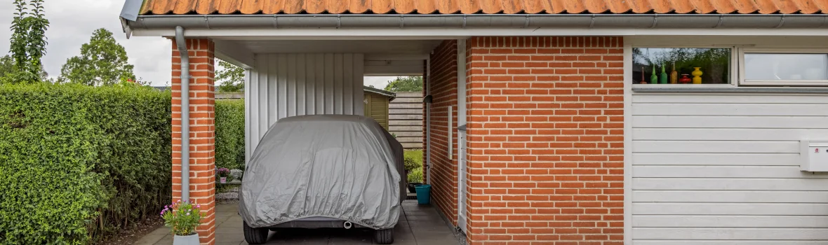 Auto mit Plane unter einem Carport an das Haus angrenzend