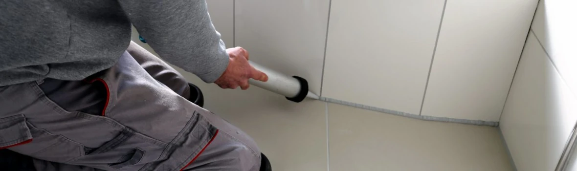 Handwerker verfugt Abschluss von Badewanne und Boden mit Silikon