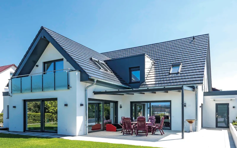 modernes weißes Einfamilienhaus mit Garten, Terrasse und Balkon und blauem Steildach