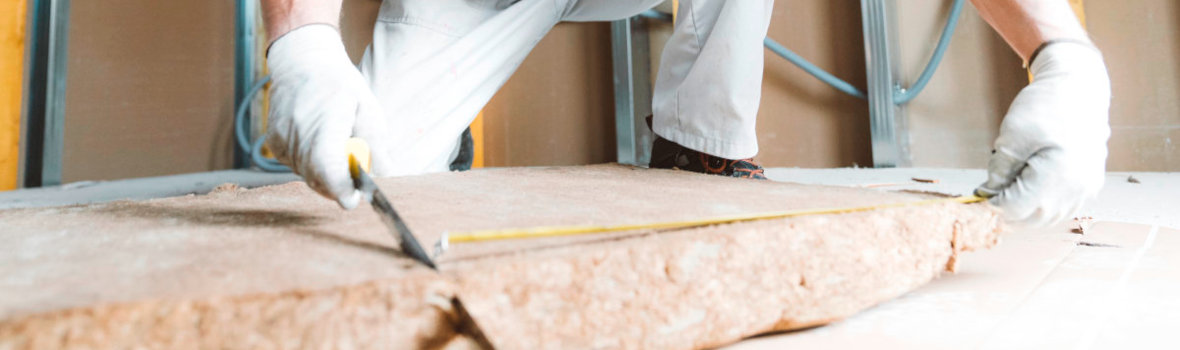 Handwerker schneidet Dämmstoff mit einem Cuttermesser 