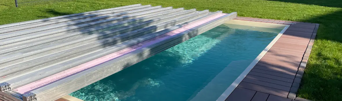 Ein mit wasserbefüllter Pool in einem Garten wird halb von einer Abdeckung verdeckt.