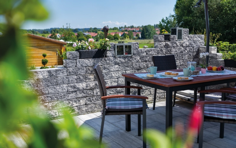 Gartenmauer mit Terrassenmöbeln der Marke KANN.