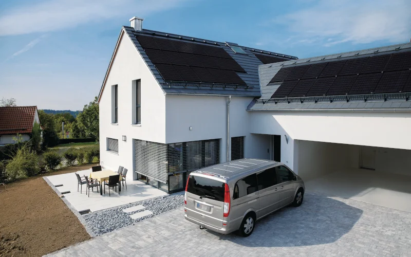 Einfamilienhause mit großer Garage, einem Auto davor und nebenliegender Terrasse