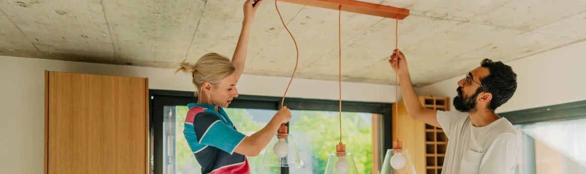 Mann und Frau bringen eine Lampe an der Decke an