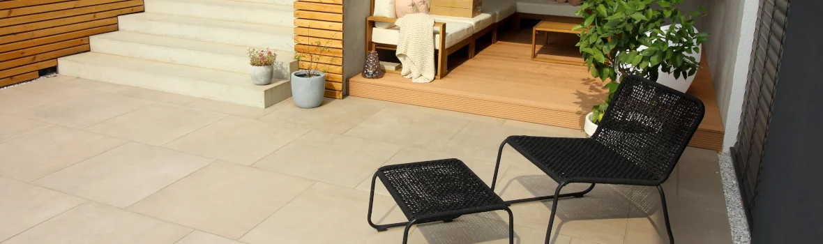 Terrasse mit Gartenstuhl und beigen Terrassenplatten und Treppenstufen im Hintergrund