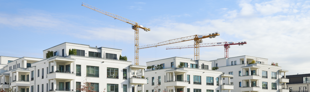 Reihe von weißen Wohnhäusern und Baustelle mit Kränen