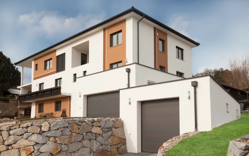 modernes Haus auf einer Empore mit Garagen und teilweise farbigem Fassadenputz