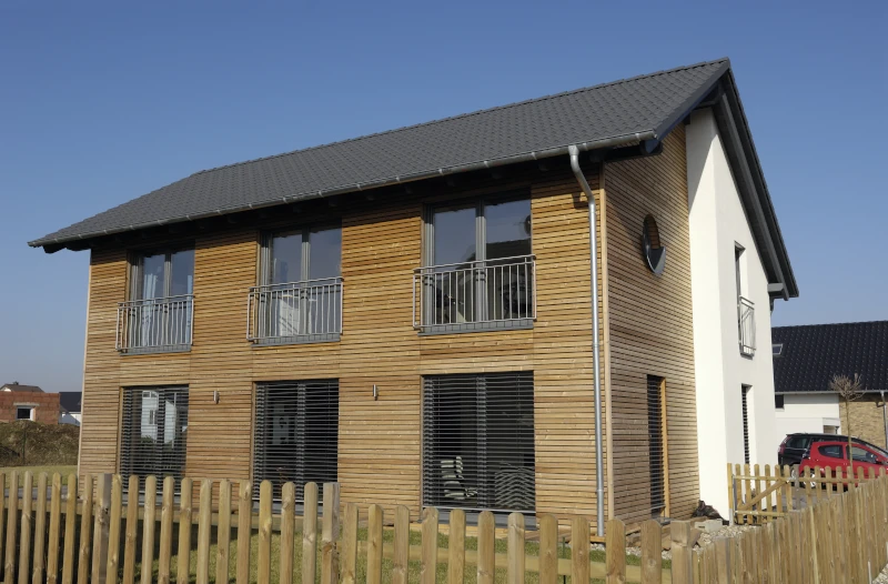 Einfamilienhaus mit Holzfassade, grauem Dach und Garten davor 