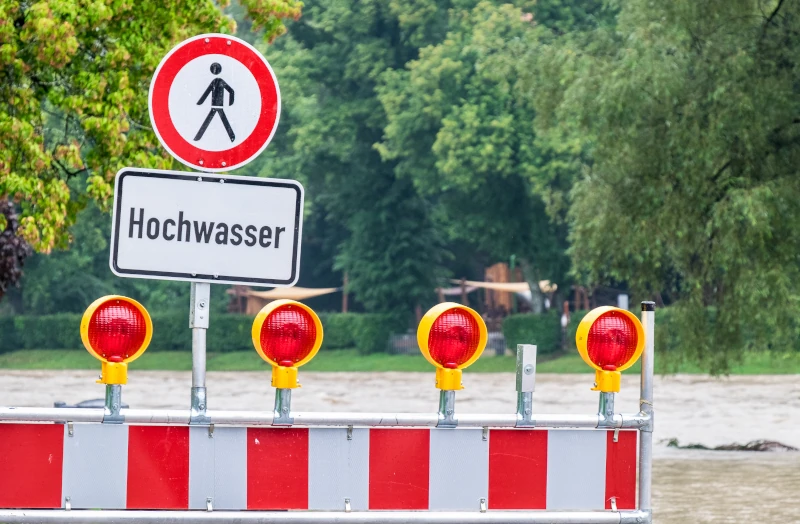 ein Überschwemmtes Gebiet mit einer Warnbarke und Warnschild im Vordergrund 