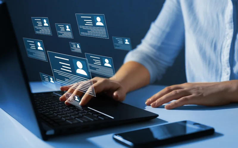 Mensch am Laptop mit digitalen Stellenanzeigen die visuell in der Luft stehen