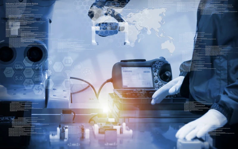 ein Arbeiter der neben einer Roboter-Fertigungsmaschine steht 