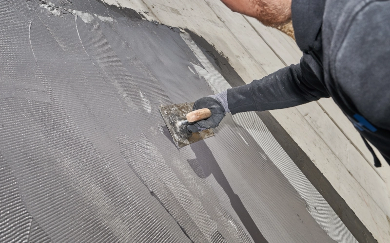 Handwerker dichtet eine Wand mit Abdichtungsmasse ab
