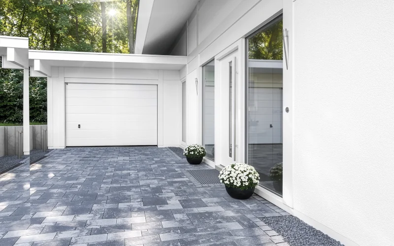 Auffahrt mit Garage und Haustür und Pflastersteinen auf dem Boden