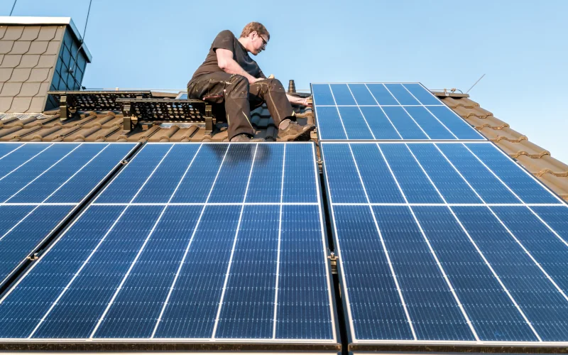 Arbeiter kontrolliert auf dem Dach befestigte Solarpaneele