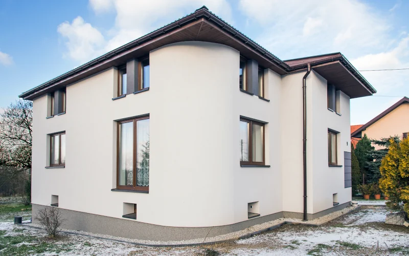 weißes modernes Wohnhaus mit leicht mit Schnee bedeckten Garten drumherum