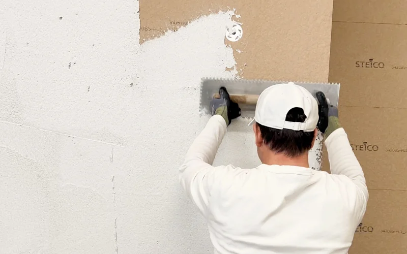 Handwerker verstreicht weiße Masse mit einer großen Kelle