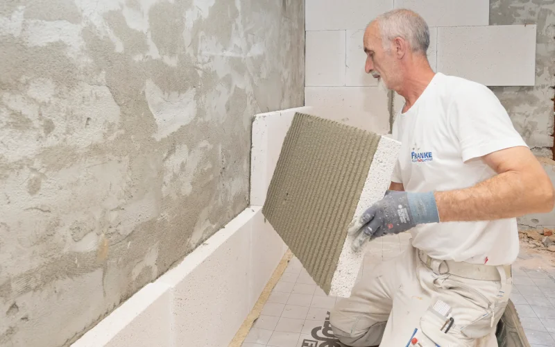 Handwerker bringt weiße Dämmplatten an Innenwand an 