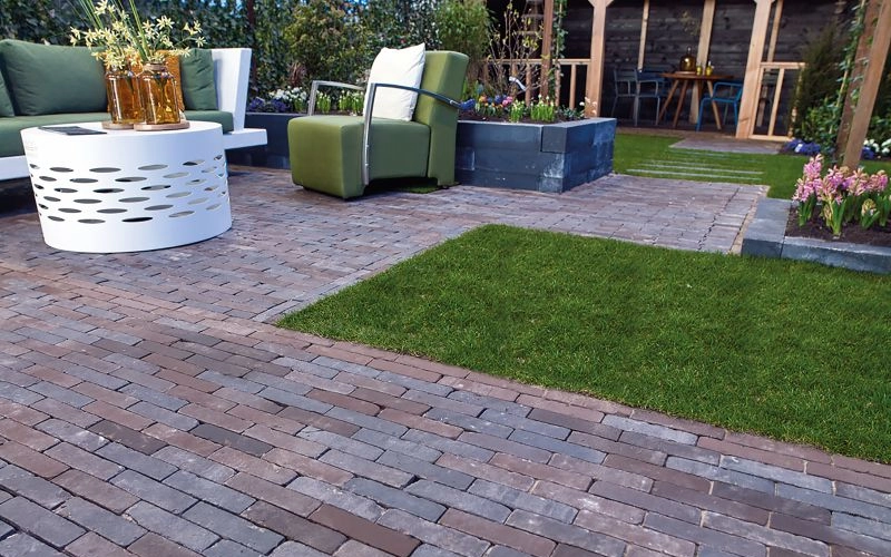 Terrasse mit Pflasterklinker und einer mittig platzierten Rasenfläche