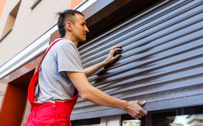 Handwerker bringt einen blau-grauen Außenrollladen an