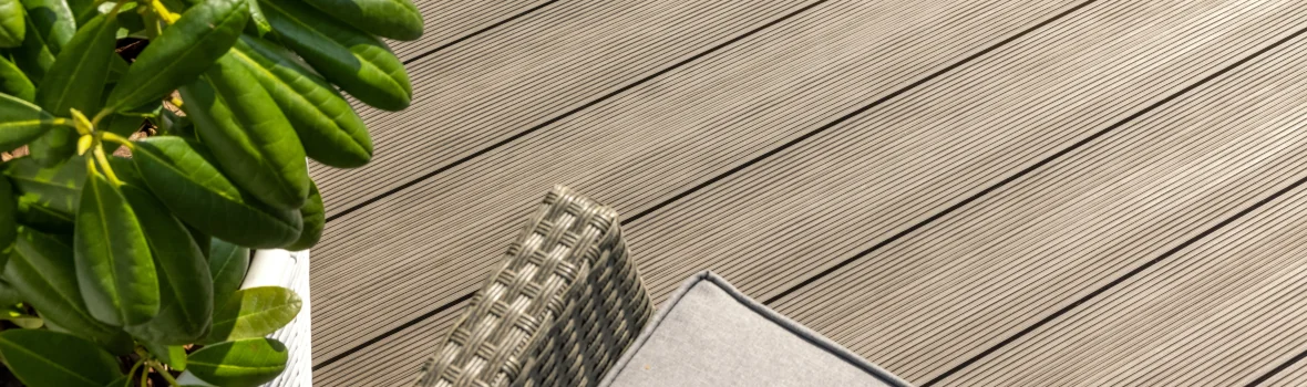 Grünpflanze und Sitzgelegenheit auf Terrassendielen stehend