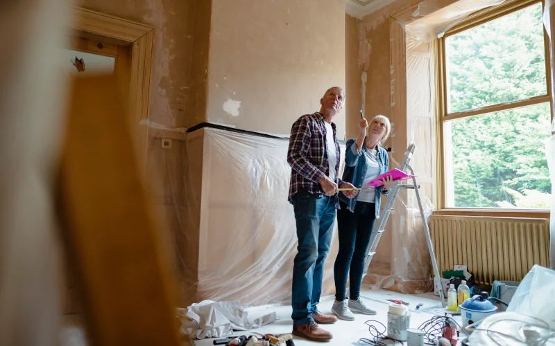 Paar steht im Wohnraum der Renoviert wird und schaut an die Decke