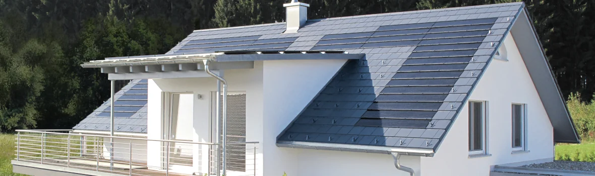 weißes, modernes Einfamilienhaus mit großem Balkon und hellgrau-blauem Dach