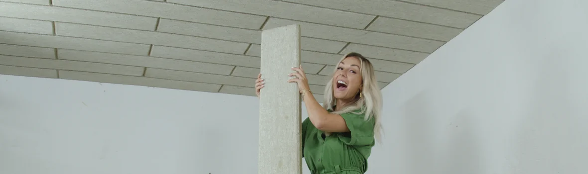 Frau im Keller mit einer Kellerdämmplatte von baumit in der Hand