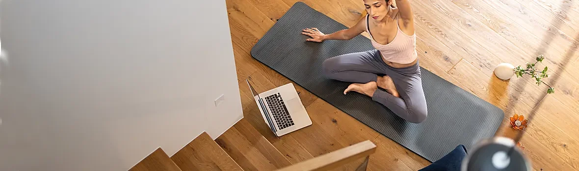 Frau sitzt auf einer Yogamatte auf dem Boden und macht Yoga