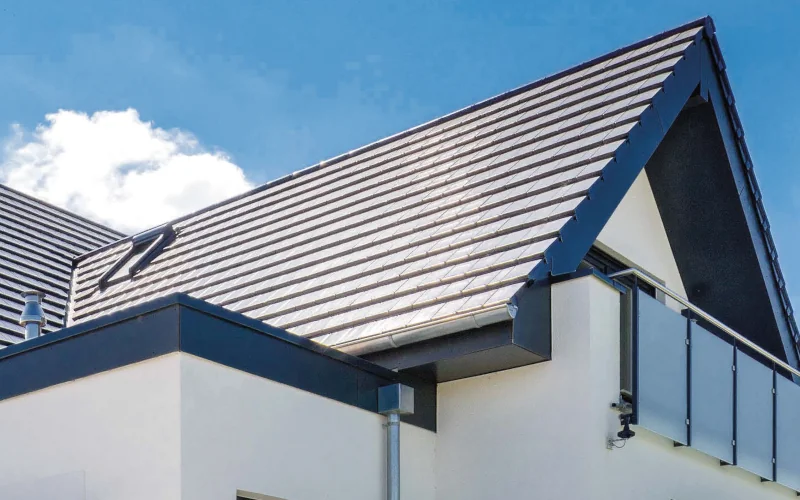 Abbildung des dunkel eingedeckten Dachbereiches eines Hauses mit Balkon.