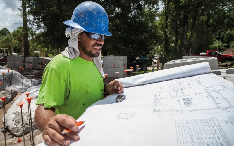 Handwerker auf einer Baustelle schaut sich den Bauplan an 