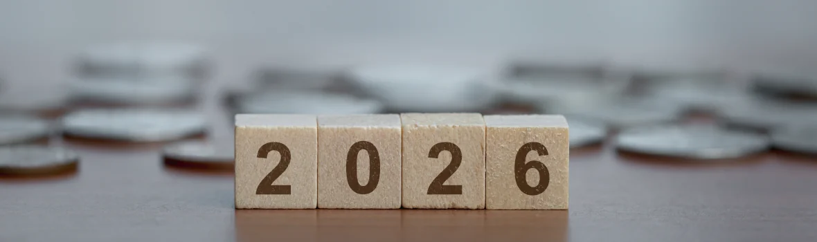 Würfel mit der Aufschrift 2, 0, 2 und 6 vor einem Häufchen Geld im Hintergrund