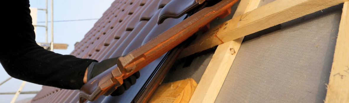 Dachdecker bringt Dachpfannen an Dachkonstruktion an