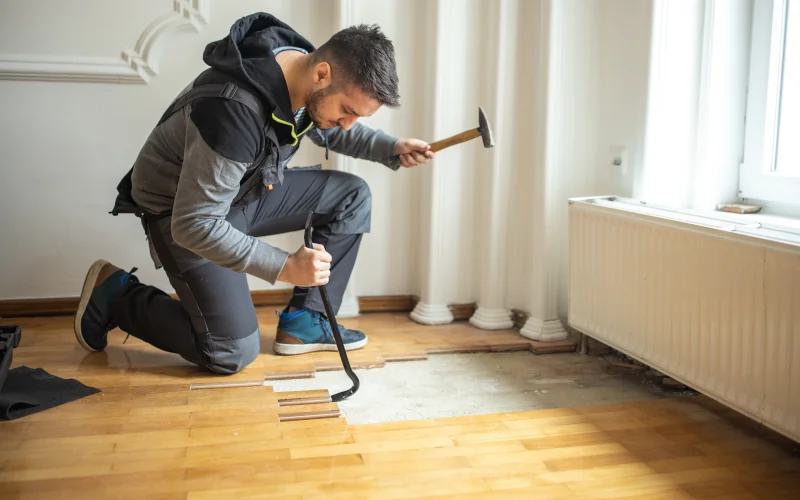 Handwerker entfernt Parkettboden in einem Wohnraum
