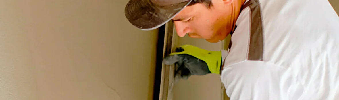 Mann streicht mit Glättescheit Masse an einer Wand glatt