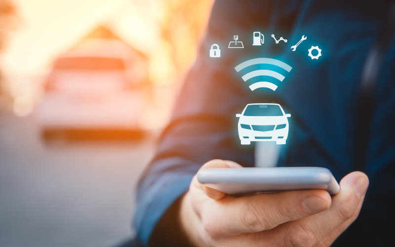 Mann mit Handy in der Hand welches Symbole zum Thema Auto projiziert 