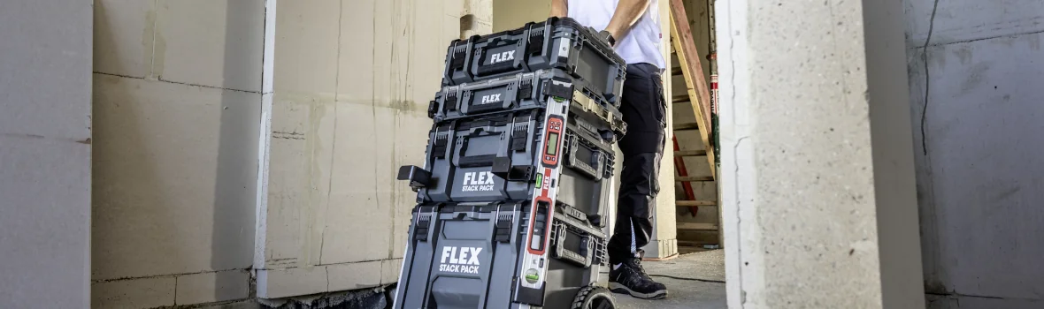 Handwerker zieht einen Aufbautrolley für Werkzeug und Baubedarf hinter sich her