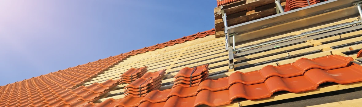 Dach im Bau nur teilweise von roten Ziegeln bedeckt 