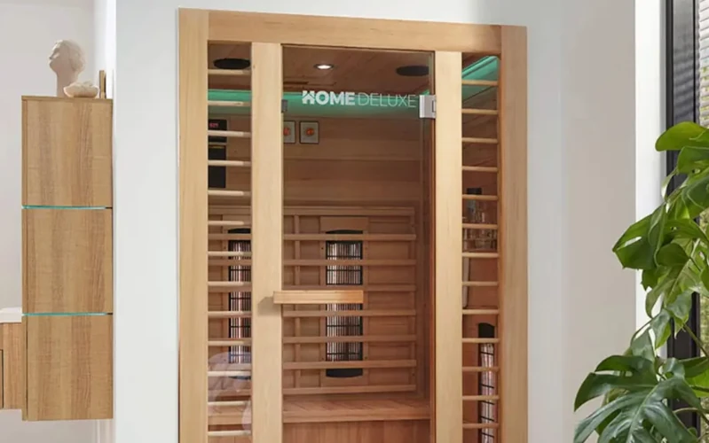 Moderne Heimsauna aus Holz, umgeben von Pflanzen.