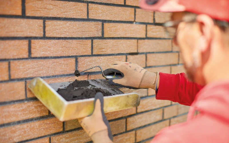 Handwerker verputzt Hauswand.