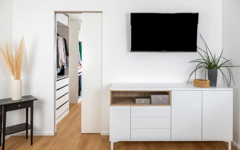 Wohnraum mit einer Schiebetür die in einen begehbaren Kleiderschrank führt