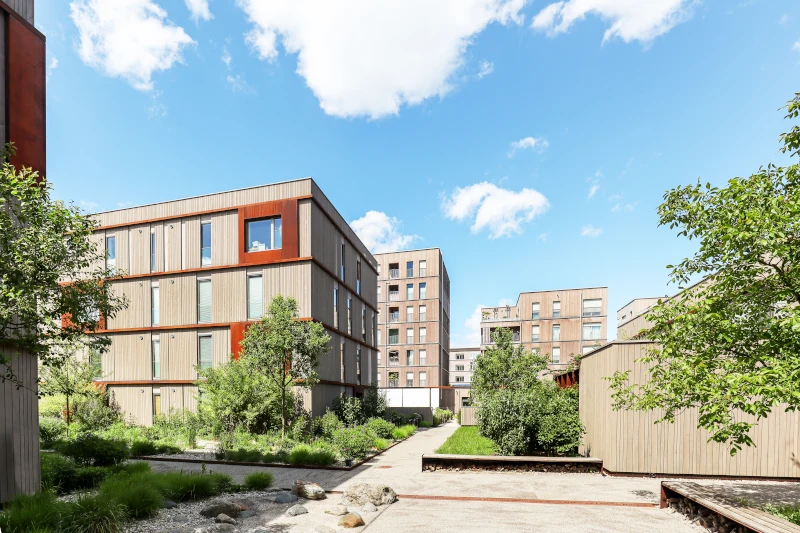 Moderne Wohnsiedlung mit Mehrfamilienhäusern in Holzbauweise und Grünanlagen.