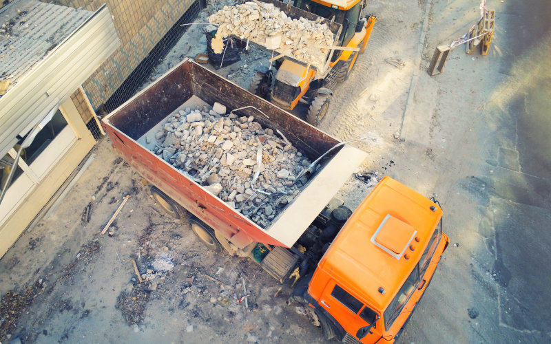 Bau-Lkw laden Schutt auf einer Baustelle ab.