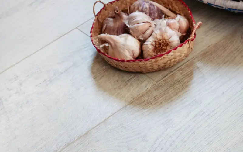Ein Körbchen mit Knoblauch auf hellem Holzboden