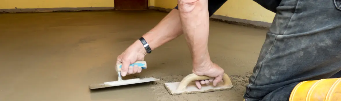 Handwerker streicht Bodenmasse mit Spachteln glatt 