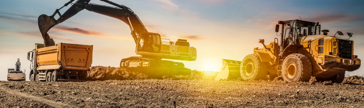 Bagger und Radlader mit der Sonne im Hintergrund