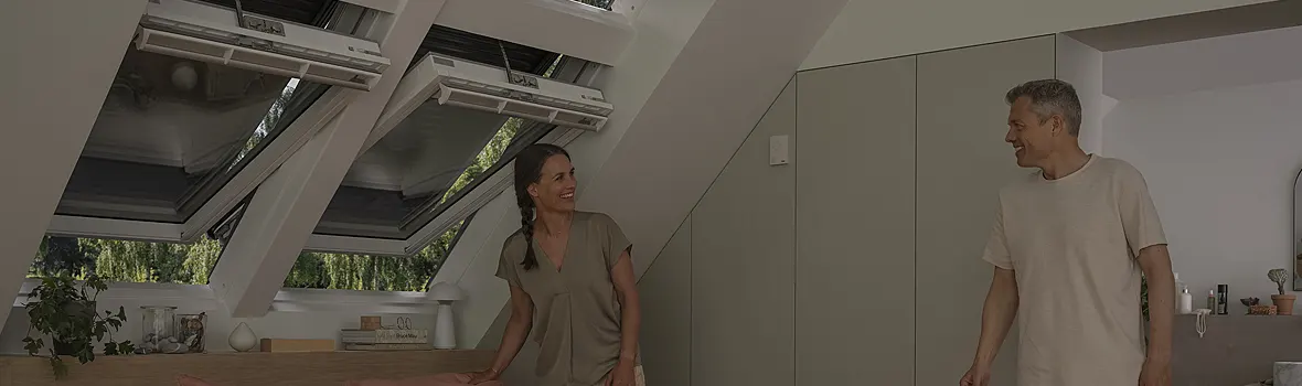 Zwei Personen in einem Schlafzimmer mit Velux-Fenstern mit geschlossenem Rolladen