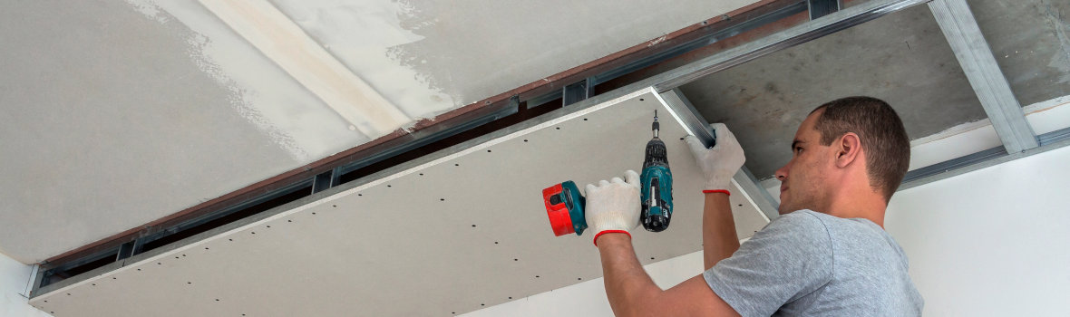 Handwerker bringt Platten an abgehängter Decke an